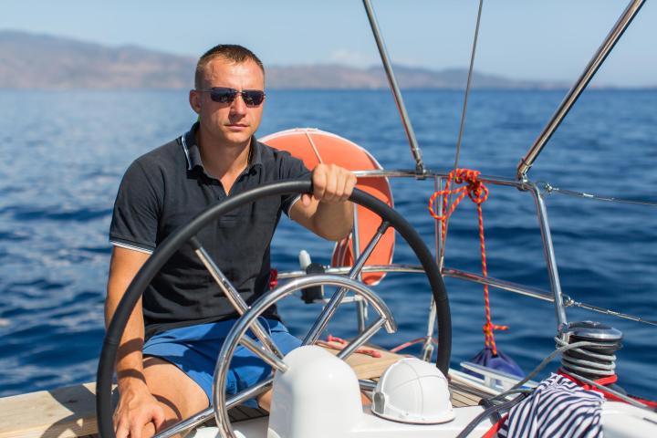 man sitting at steering wheel of boat